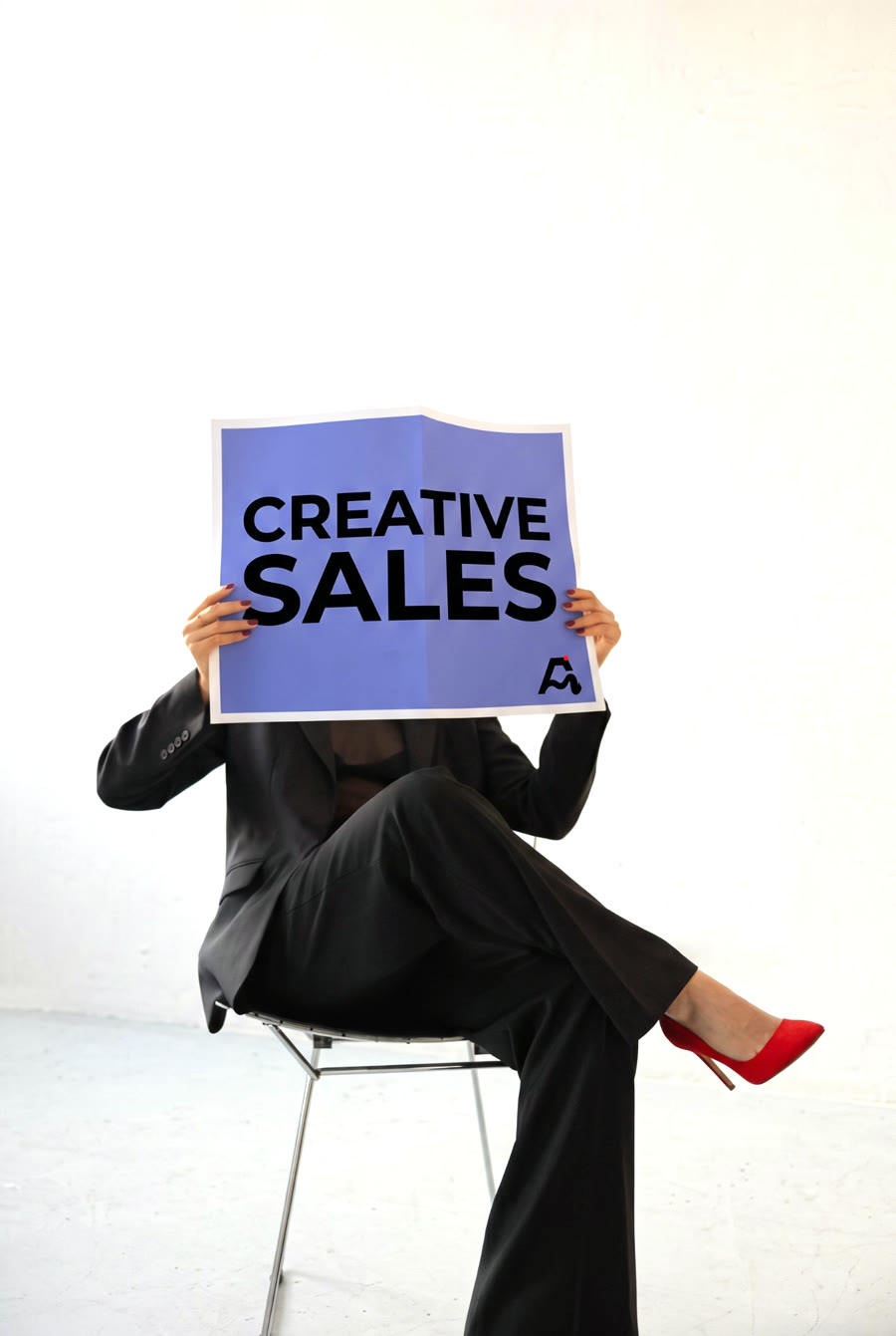 Persona sentada sosteniendo un cartel de Merkads con el texto «Creative Sales»